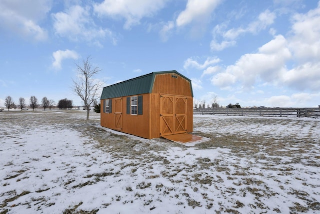 snow covered structure with an outbuilding and a rural view