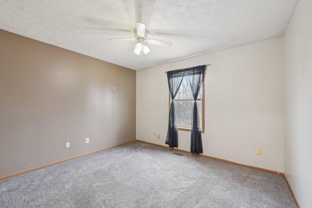 empty room with a textured ceiling, carpet floors, a ceiling fan, and baseboards