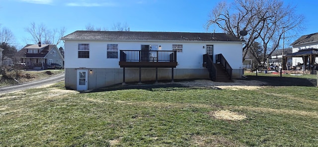 back of property featuring a wooden deck and a lawn