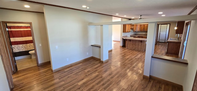 kitchen featuring dark hardwood / wood-style flooring, sink, crown molding, and kitchen peninsula