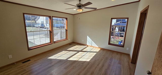 spare room with hardwood / wood-style flooring, ornamental molding, plenty of natural light, and ceiling fan