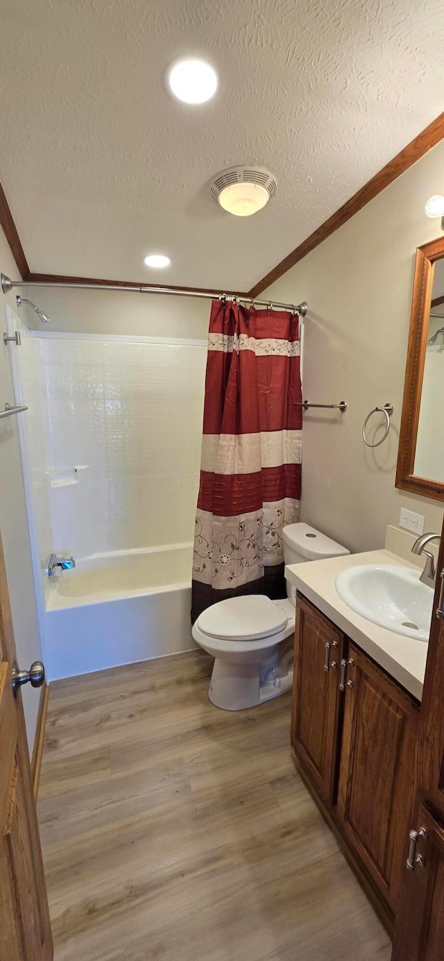 full bathroom with hardwood / wood-style floors, shower / bath combination with curtain, vanity, ornamental molding, and a textured ceiling