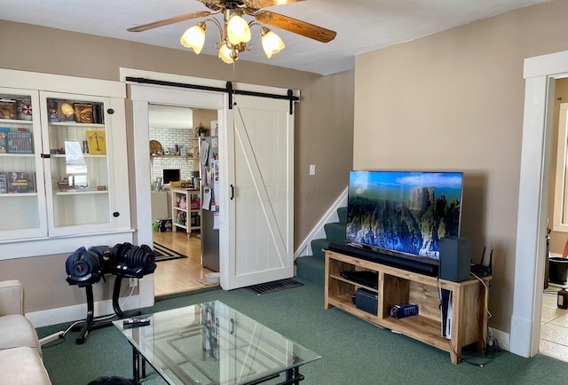 living room with carpet flooring, ceiling fan, and a barn door