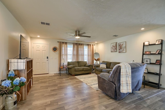 living room featuring ceiling fan, hardwood / wood-style floors, and a textured ceiling