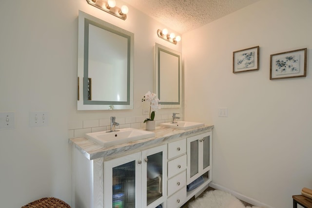 bathroom with vanity, backsplash, and a textured ceiling