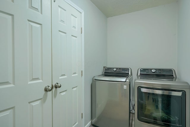 laundry area with a textured ceiling and washing machine and clothes dryer