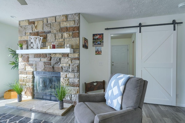 living room featuring dark hardwood / wood-style floors, a fireplace, a barn door, and a textured ceiling