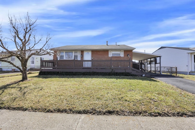 view of front facade with a front yard, aphalt driveway, a carport, and brick siding