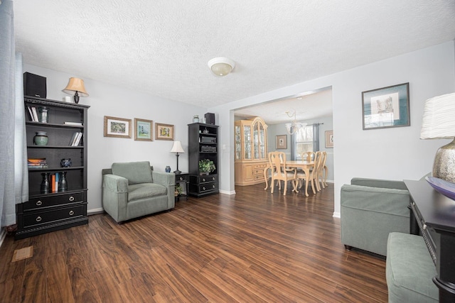 living area with a textured ceiling, dark wood-style flooring, and baseboards