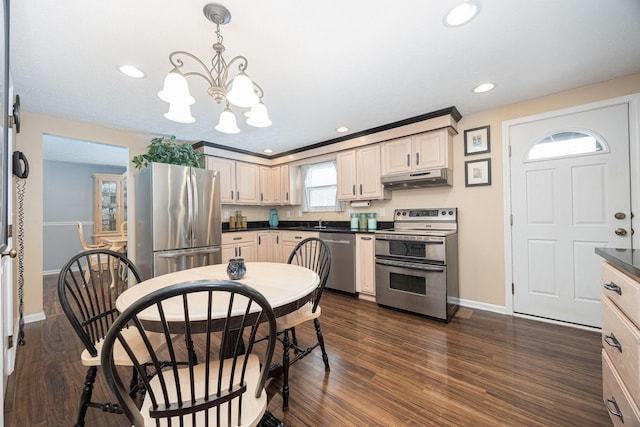 kitchen featuring dark wood finished floors, dark countertops, appliances with stainless steel finishes, under cabinet range hood, and pendant lighting