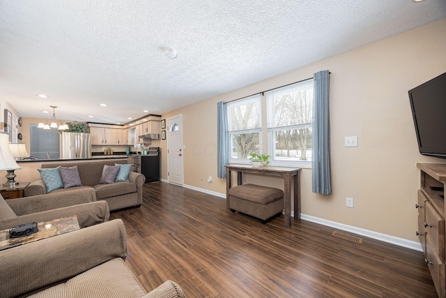 living area featuring baseboards, visible vents, dark wood finished floors, a textured ceiling, and a notable chandelier