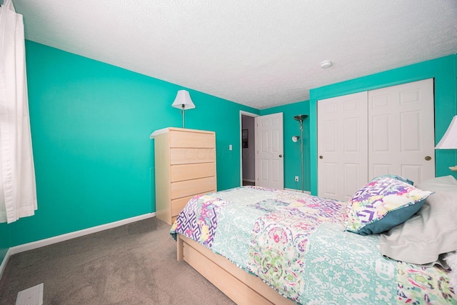 carpeted bedroom with baseboards, a textured ceiling, visible vents, and a closet