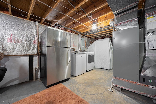 unfinished basement with freestanding refrigerator, electric panel, concrete block wall, and washing machine and clothes dryer