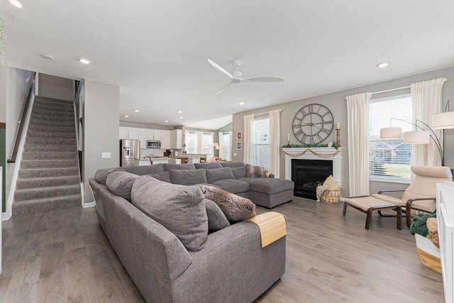 living room featuring ceiling fan, a textured ceiling, and light hardwood / wood-style flooring