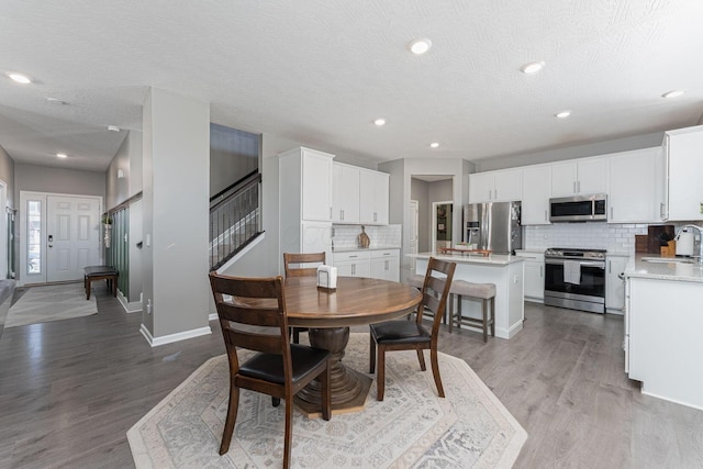 dining area featuring sink, hardwood / wood-style floors, and a textured ceiling