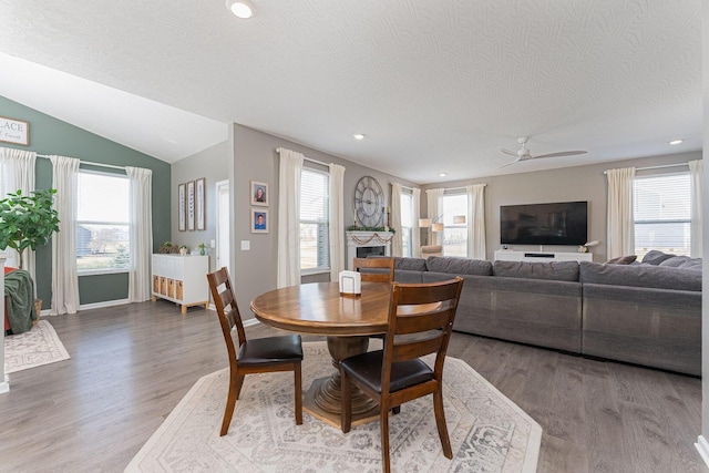 dining area featuring a wealth of natural light, vaulted ceiling, hardwood / wood-style floors, and a textured ceiling