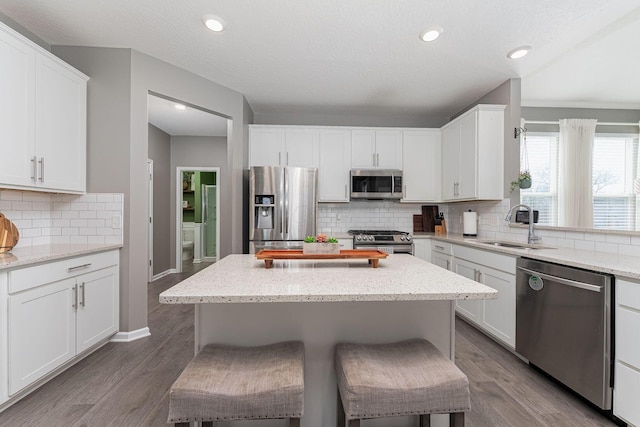 kitchen featuring white cabinetry, stainless steel appliances, a kitchen bar, and sink