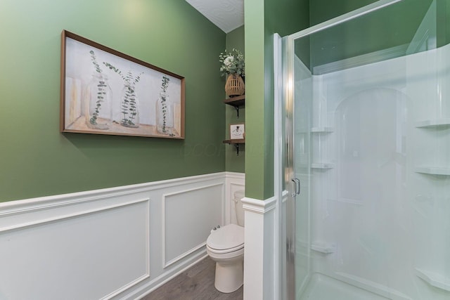 bathroom with toilet, hardwood / wood-style floors, and a shower with shower door