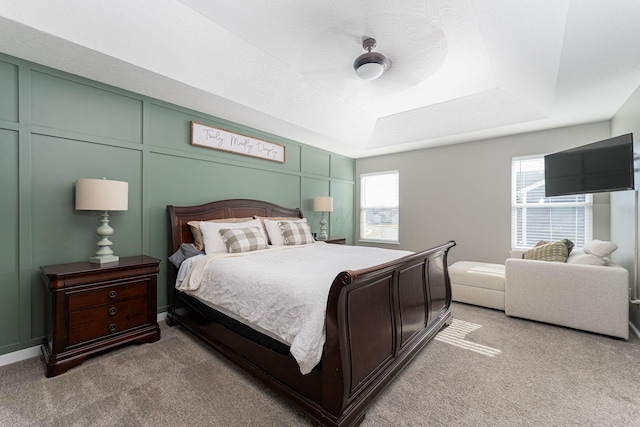 bedroom featuring multiple windows, a tray ceiling, and light colored carpet