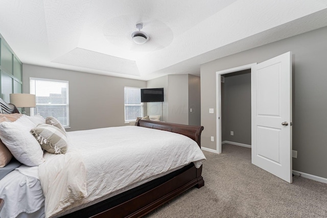 bedroom featuring ceiling fan, a raised ceiling, light carpet, and a textured ceiling