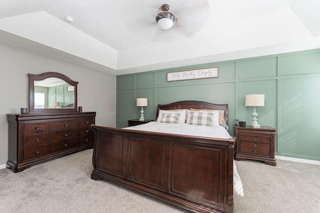 carpeted bedroom with ceiling fan, lofted ceiling, and a tray ceiling