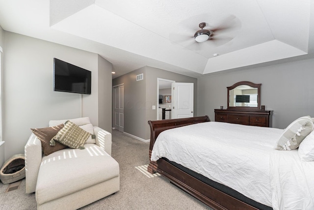 bedroom featuring light carpet, a tray ceiling, a closet, and ceiling fan