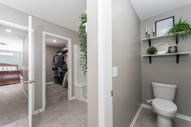 bathroom featuring a shower with door, tile patterned floors, toilet, and a textured ceiling