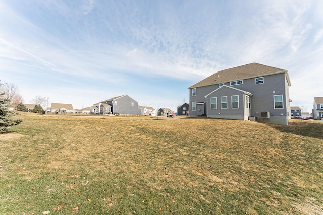 rear view of property featuring a yard and central air condition unit