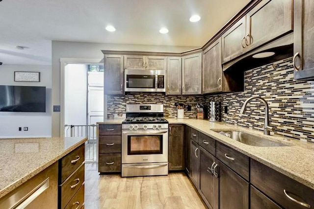 kitchen with light stone counters, dark brown cabinetry, stainless steel appliances, and sink