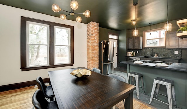 kitchen featuring appliances with stainless steel finishes, decorative light fixtures, sink, a breakfast bar area, and backsplash