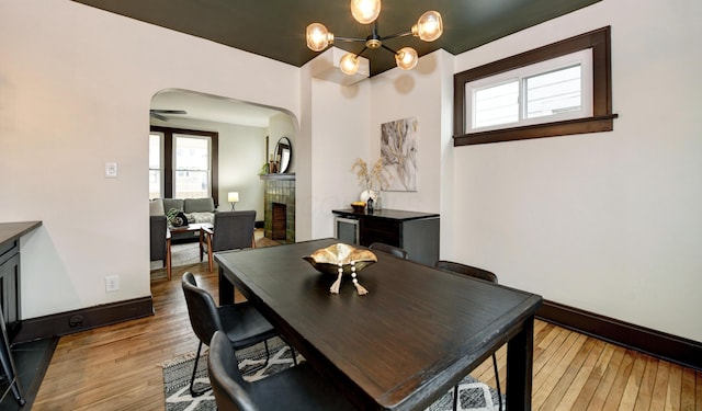 dining room with an inviting chandelier, a fireplace, and light hardwood / wood-style flooring