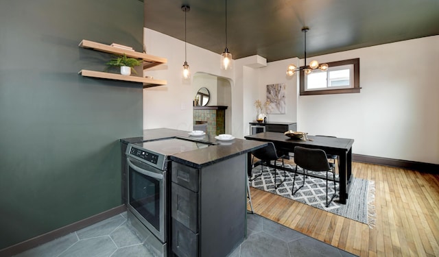 kitchen with dark hardwood / wood-style floors, decorative light fixtures, kitchen peninsula, and stainless steel electric range