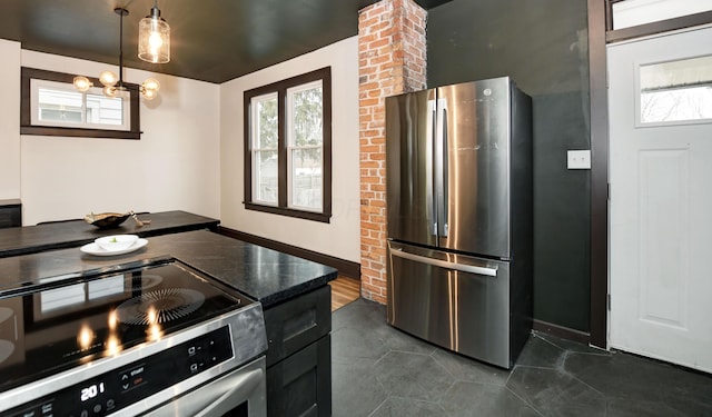 kitchen with appliances with stainless steel finishes, dark tile patterned flooring, a chandelier, and decorative light fixtures