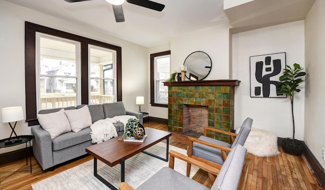 living room featuring hardwood / wood-style flooring, a tiled fireplace, and ceiling fan