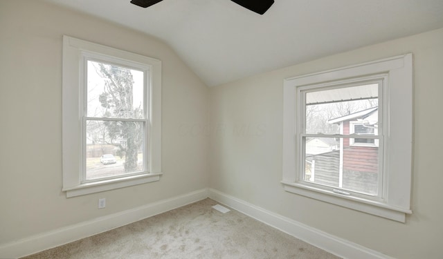 empty room featuring ceiling fan, light colored carpet, lofted ceiling, and a wealth of natural light