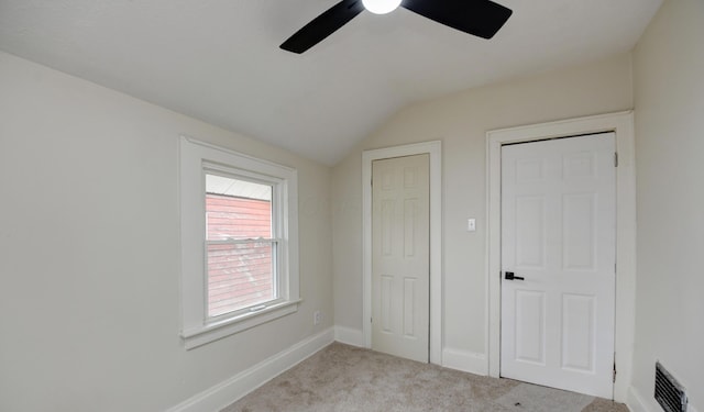 unfurnished bedroom featuring vaulted ceiling, light colored carpet, and ceiling fan