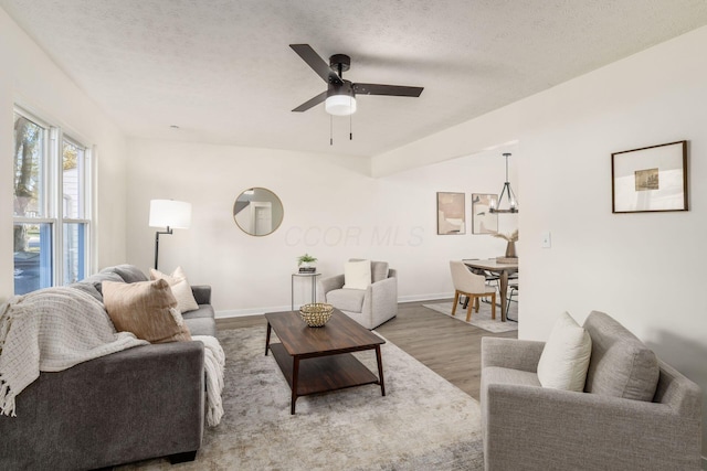 living room featuring ceiling fan, wood-type flooring, and a textured ceiling