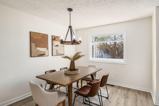 dining area with hardwood / wood-style flooring, a chandelier, and a textured ceiling