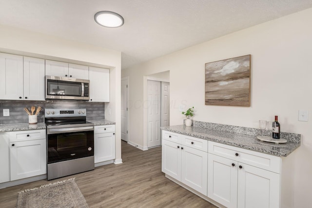 kitchen with white cabinetry, stainless steel appliances, and decorative backsplash