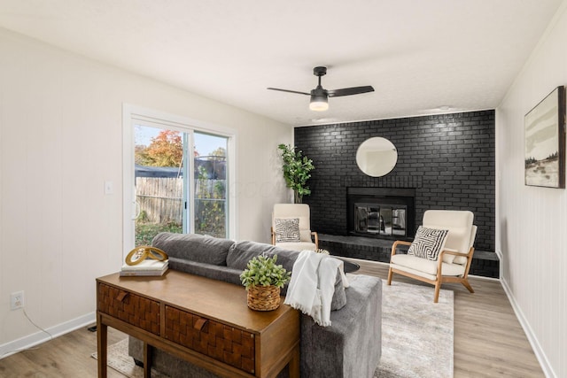 living room with ceiling fan, a fireplace, and light hardwood / wood-style floors