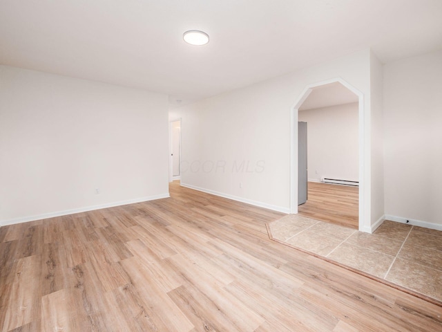 spare room featuring a baseboard radiator and light hardwood / wood-style floors