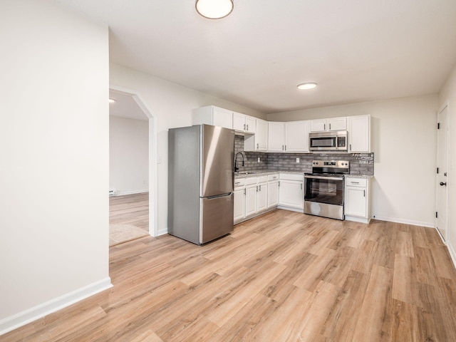 kitchen with appliances with stainless steel finishes, sink, decorative backsplash, and white cabinets