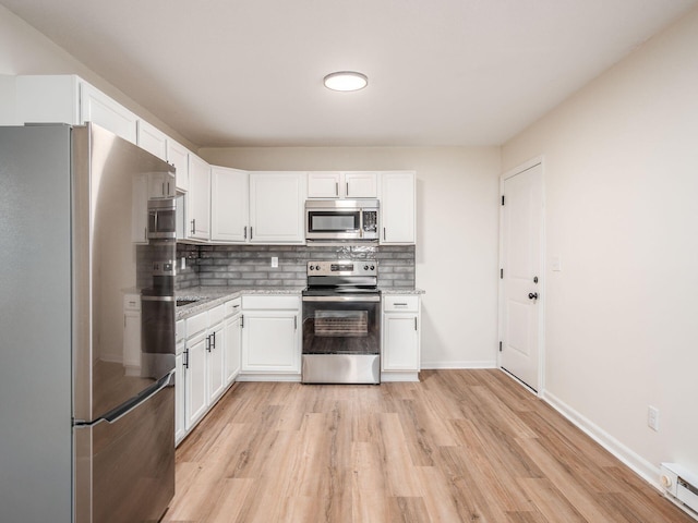 kitchen featuring appliances with stainless steel finishes, white cabinetry, backsplash, light stone countertops, and light hardwood / wood-style flooring