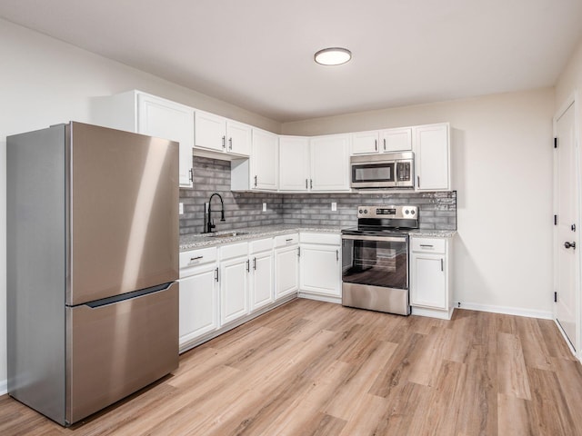 kitchen with sink, white cabinetry, light hardwood / wood-style flooring, stainless steel appliances, and light stone countertops