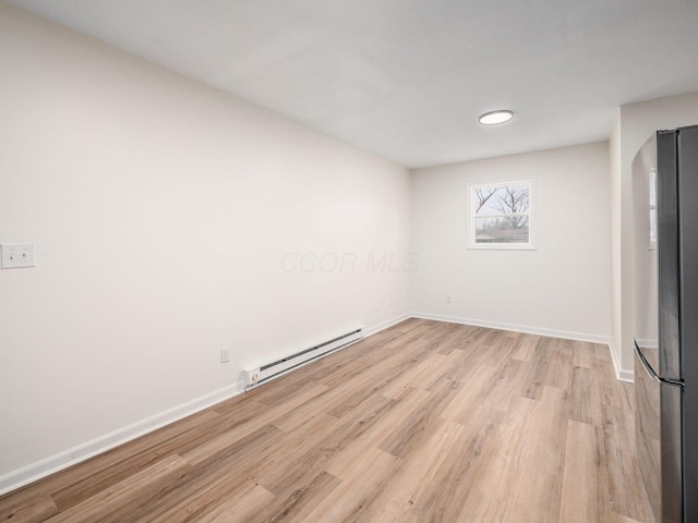 empty room featuring baseboard heating and light hardwood / wood-style flooring