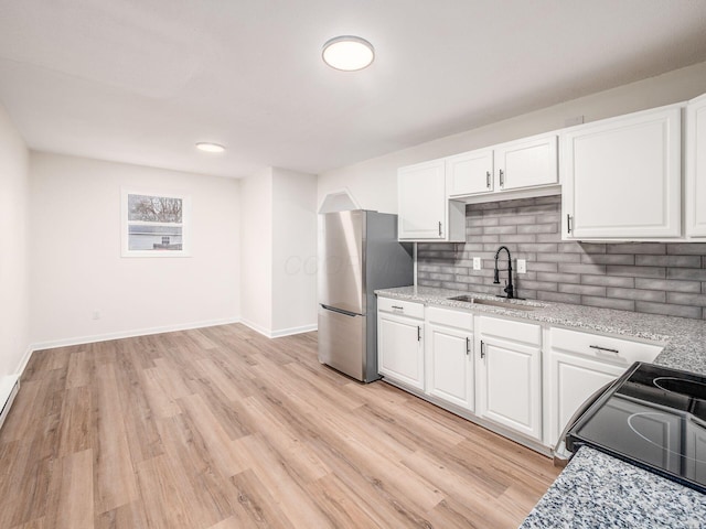 kitchen with white cabinetry, stainless steel fridge, and sink