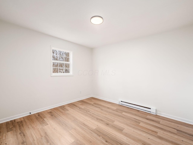 unfurnished room featuring a baseboard heating unit and light hardwood / wood-style floors