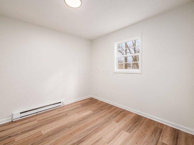 empty room with baseboard heating and light hardwood / wood-style floors