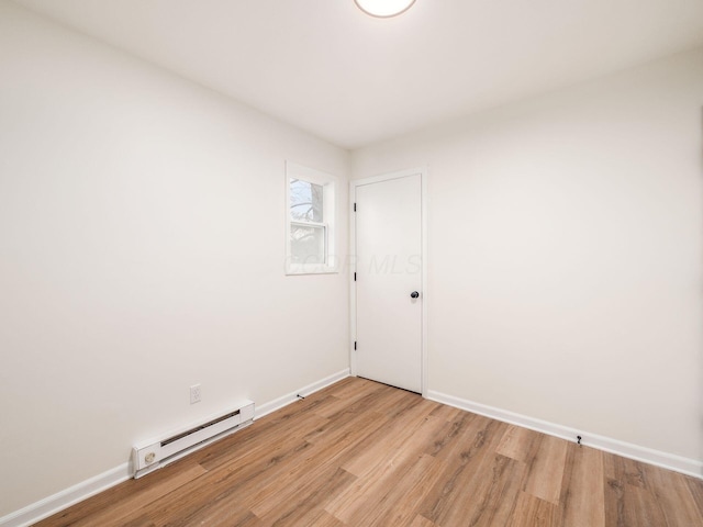 spare room with a baseboard heating unit and light hardwood / wood-style floors