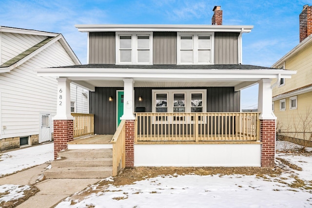 american foursquare style home with a porch and board and batten siding